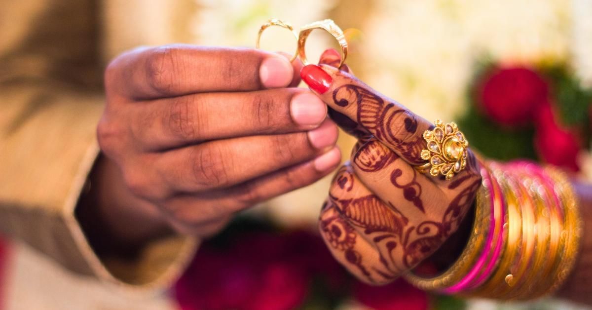 Pakistani bride and groom holding rings at Gorse Hill in Surrey
