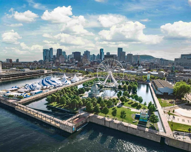 Aerial view of Montreal's Old Port featuring a Ferris wheel, striped tents, and city skyline at Warwick Le Crystal Montreal