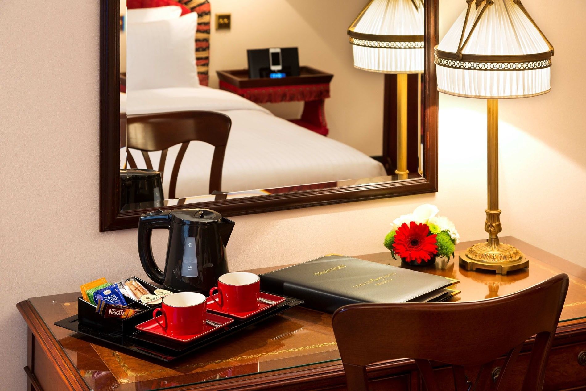 Red coffee cups and a black kettle on a polished wooden work desk at Hotel Barsey by Warwick