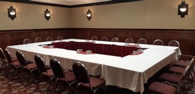 Hollow square meeting table with white linens, chairs surrounding under wall sconces at The Glenmore Inn