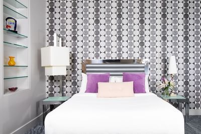 Comfy bed, lamps & patterned wallpaper in Queen Premiere Blast at Retro Suites Hotel