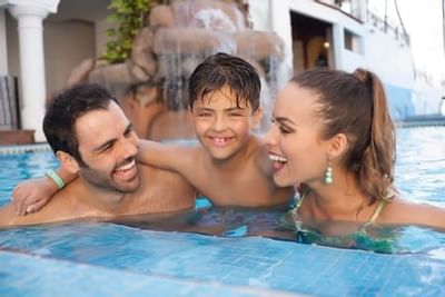 Happy family of three enjoying quality time together in the resort pool at Playa Los Arcos Puerto Vallarta 2023