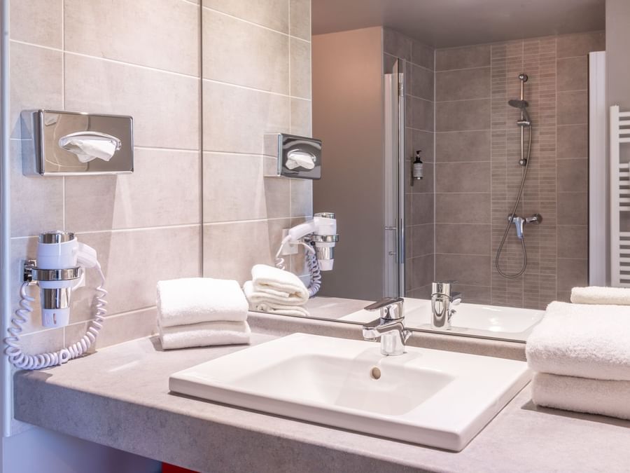 Bathroom with a wash basin and bathtub at The Originals Hotels