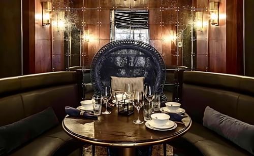 White Lotus restaurant in Paradox Vancouver with wooden tables and benches, featuring reflective walls and an a chandellier