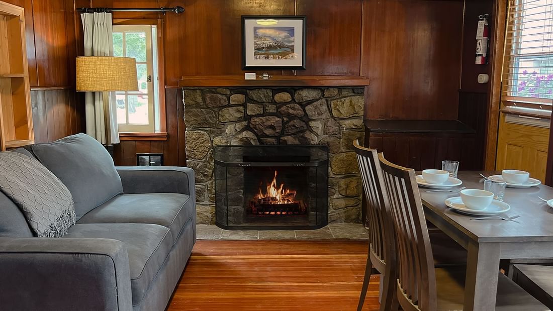 Cabin with couch, table, chairs, and fire place