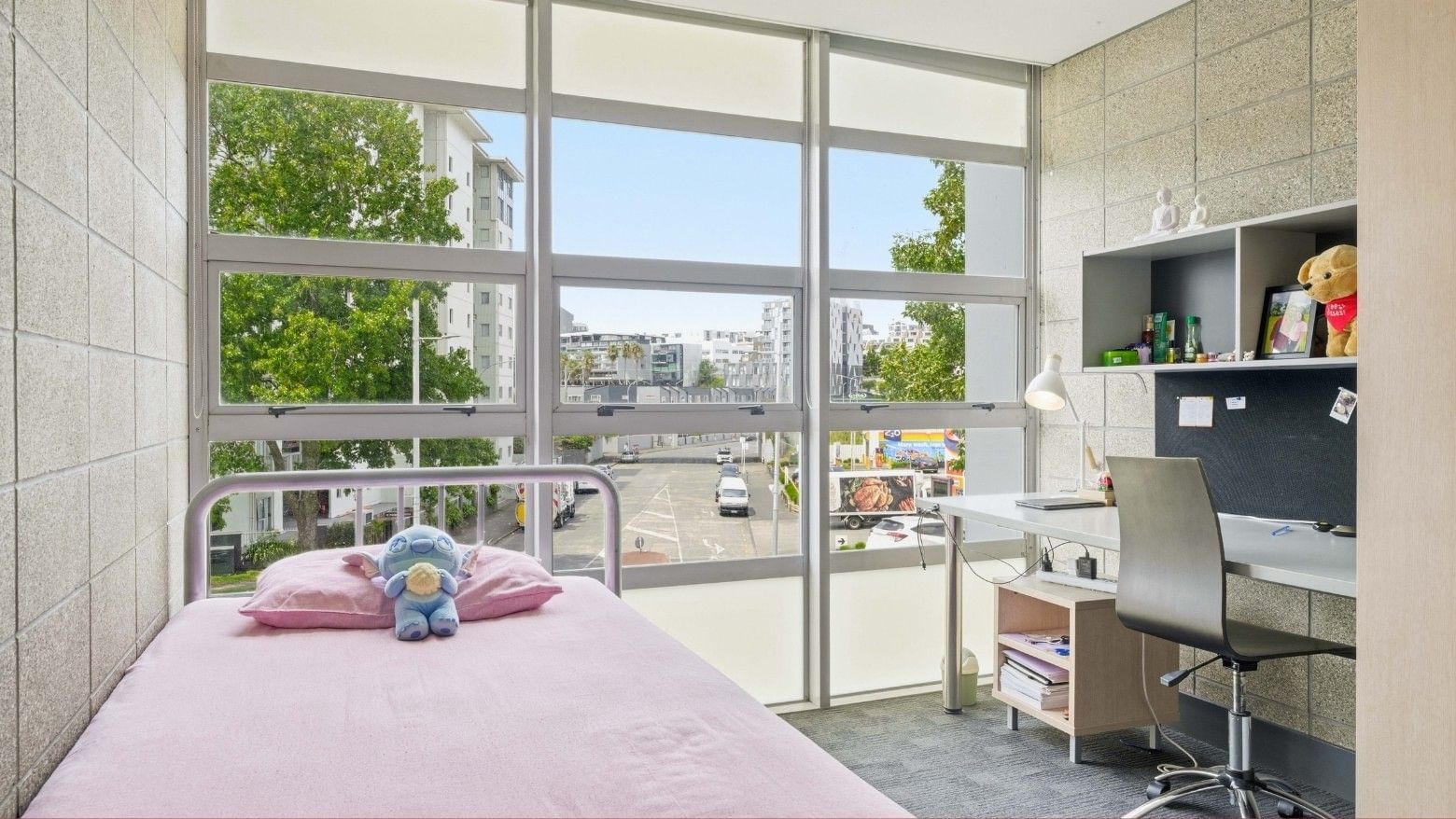 A student room with a bed, desk, and stuffed toy at Student Living Auckland Beach.