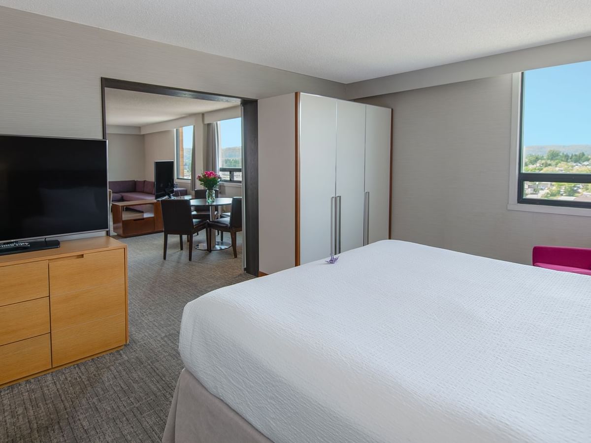 Hotel suite with king bed, TV, living area, and a window with a view.