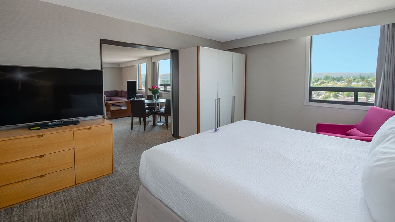 Hotel suite with king bed, TV, living area, and a window with a view.