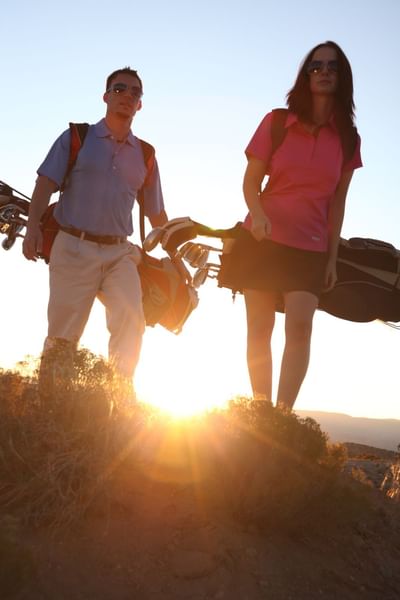 Sunset silhouettes golfers with their bags at Hilton Santa Fe Buffalo Thunder