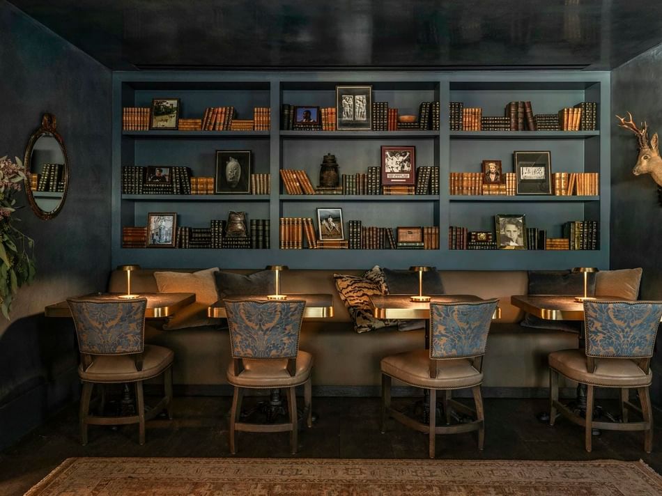 Cozy reading nook in The Granduca Library at Granduca Houston with plush chairs, warm lighting, and book walls