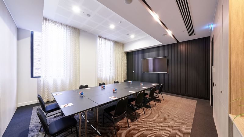 Boardroom set up facing the wall-mounted TV in The Hub at Ibis Adelaide