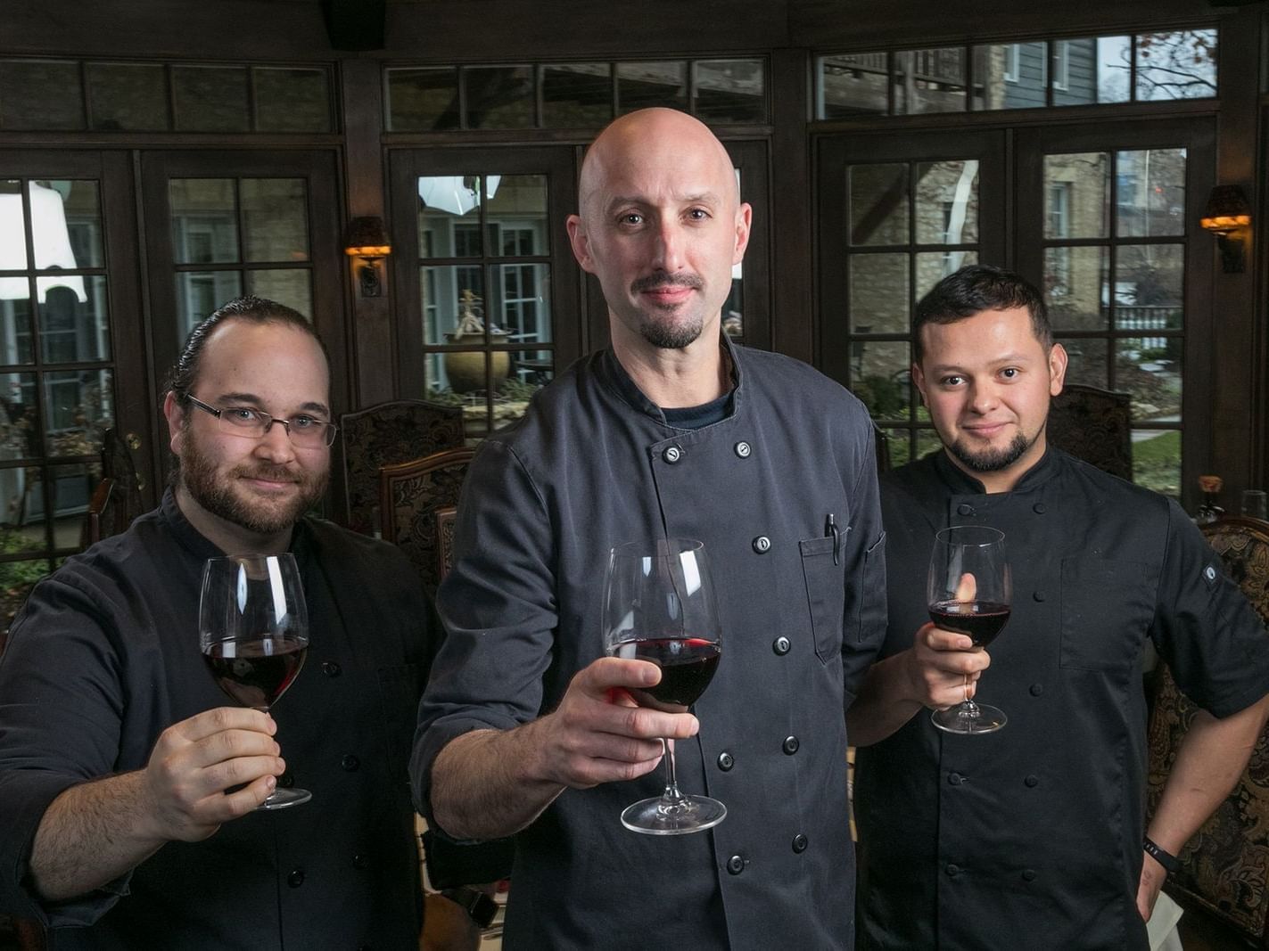 three chefs holding glasses of red wine