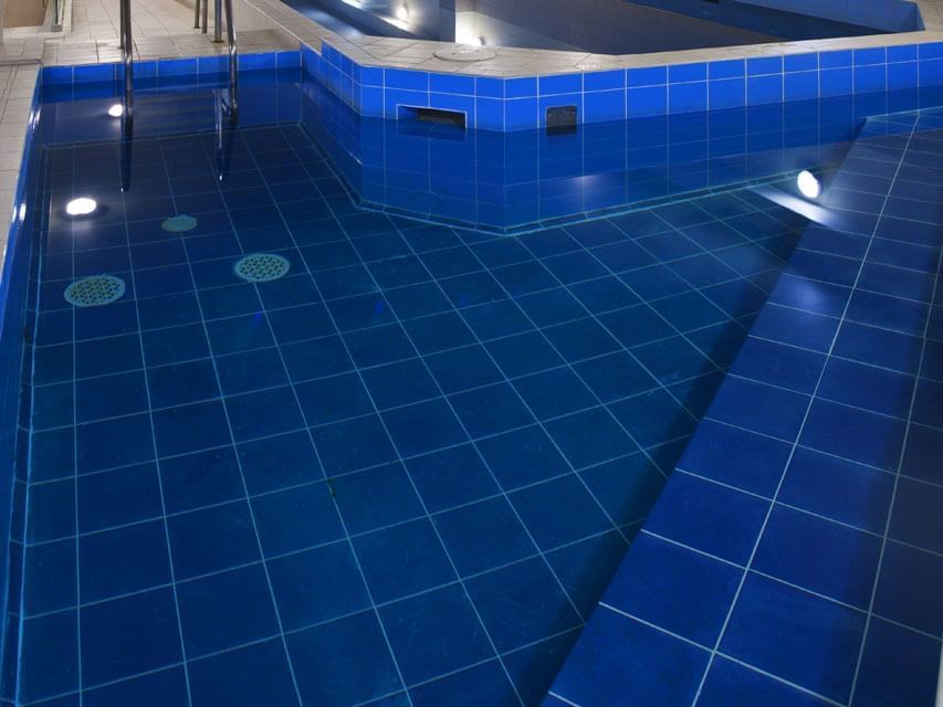 Heated indoor swimming pool area with lights at Hotel Grand Chancellor