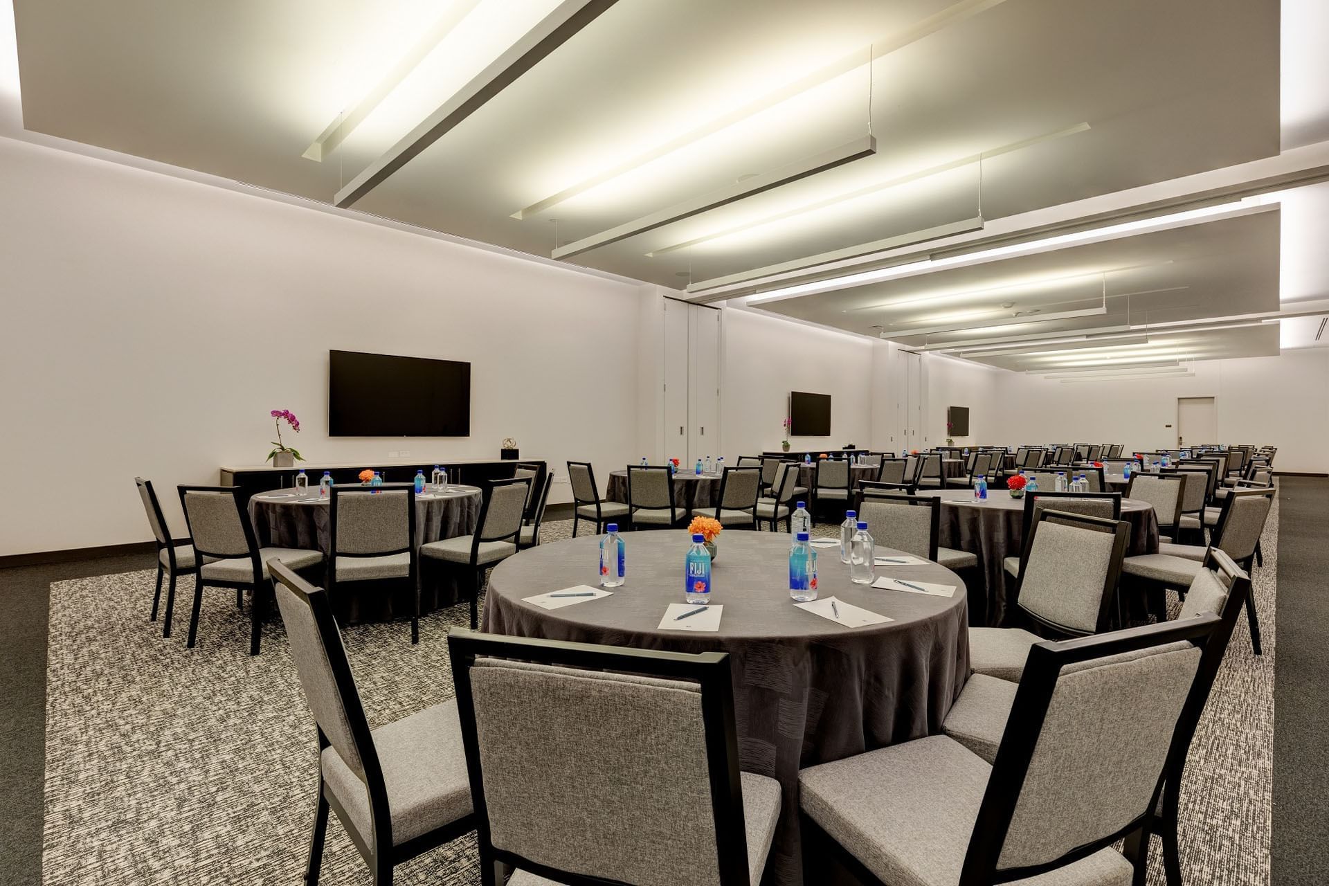 Cabaret set-up in Coronation Park with round tables and grey chairs set under bright ceiling lights at Hotel X Toronto