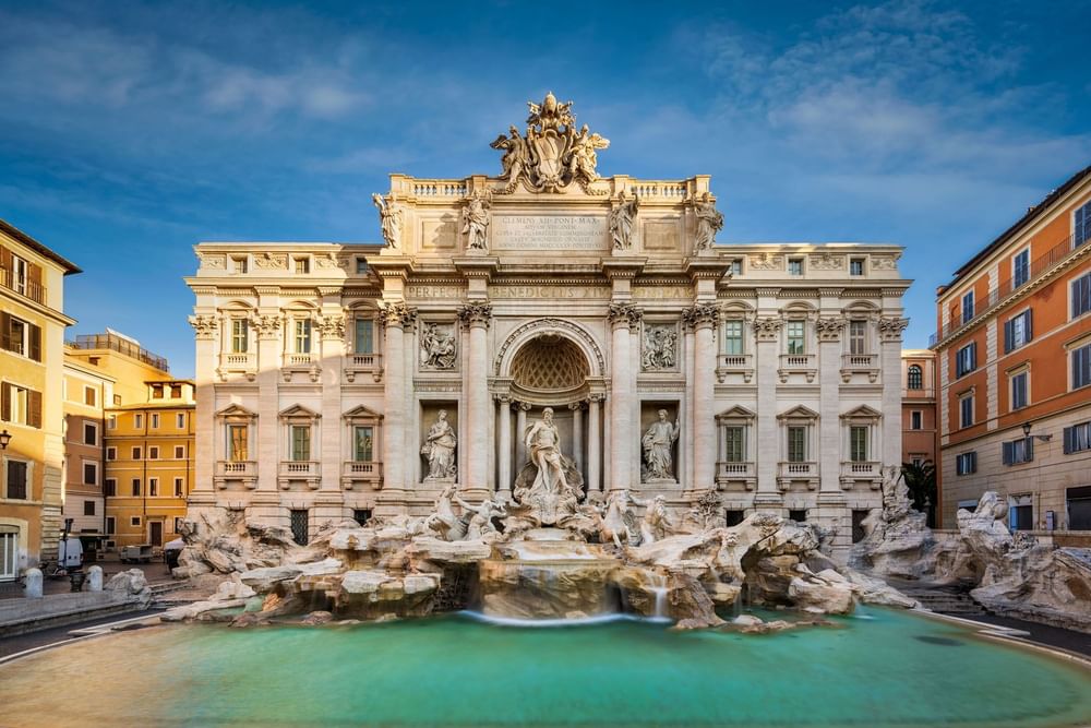 Dazzling Trevi Fountain with grand sculptures, cascading water & pool under a clear sky near The Guardian Hotel