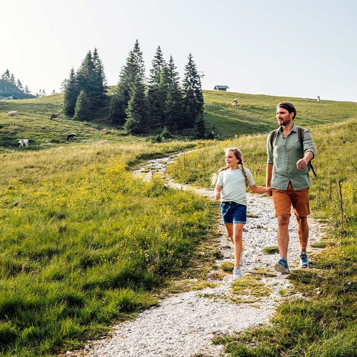 Padre e figlia camminano su un sentiero di campagna in una giornata di sole.