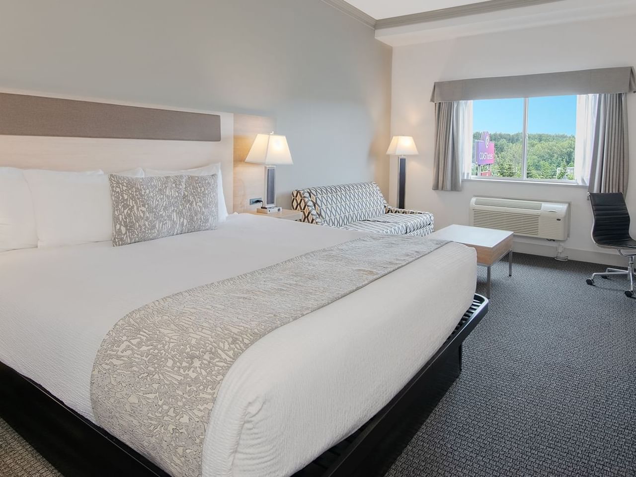Hotel room with king bed, couch, coffee table, window, mirror, chair and desk