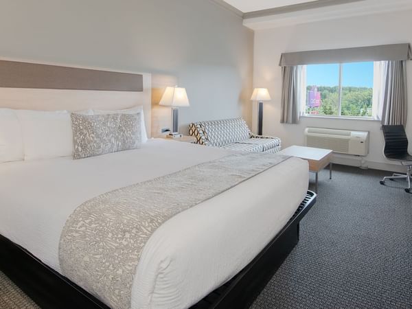 Hotel room with king bed, TV, couch, coffee table, chair and window