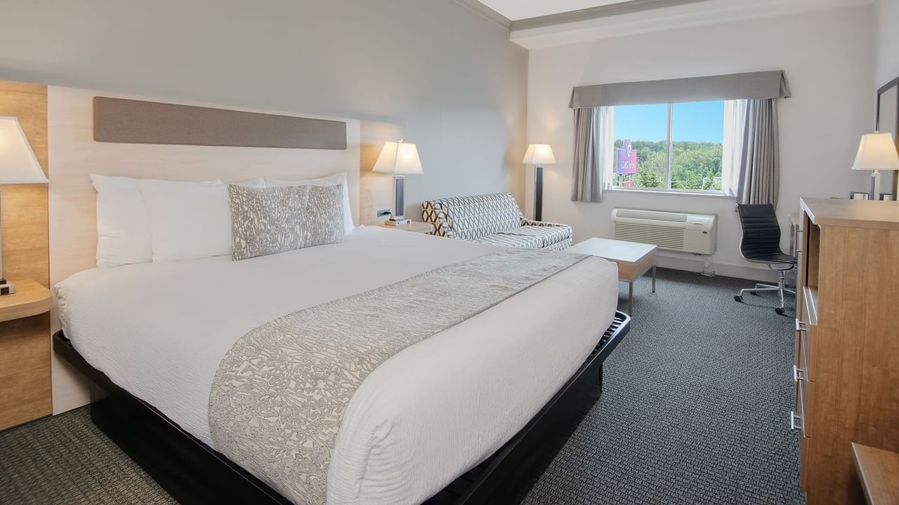 Hotel room with king bed, TV, couch, coffee table, chair and window