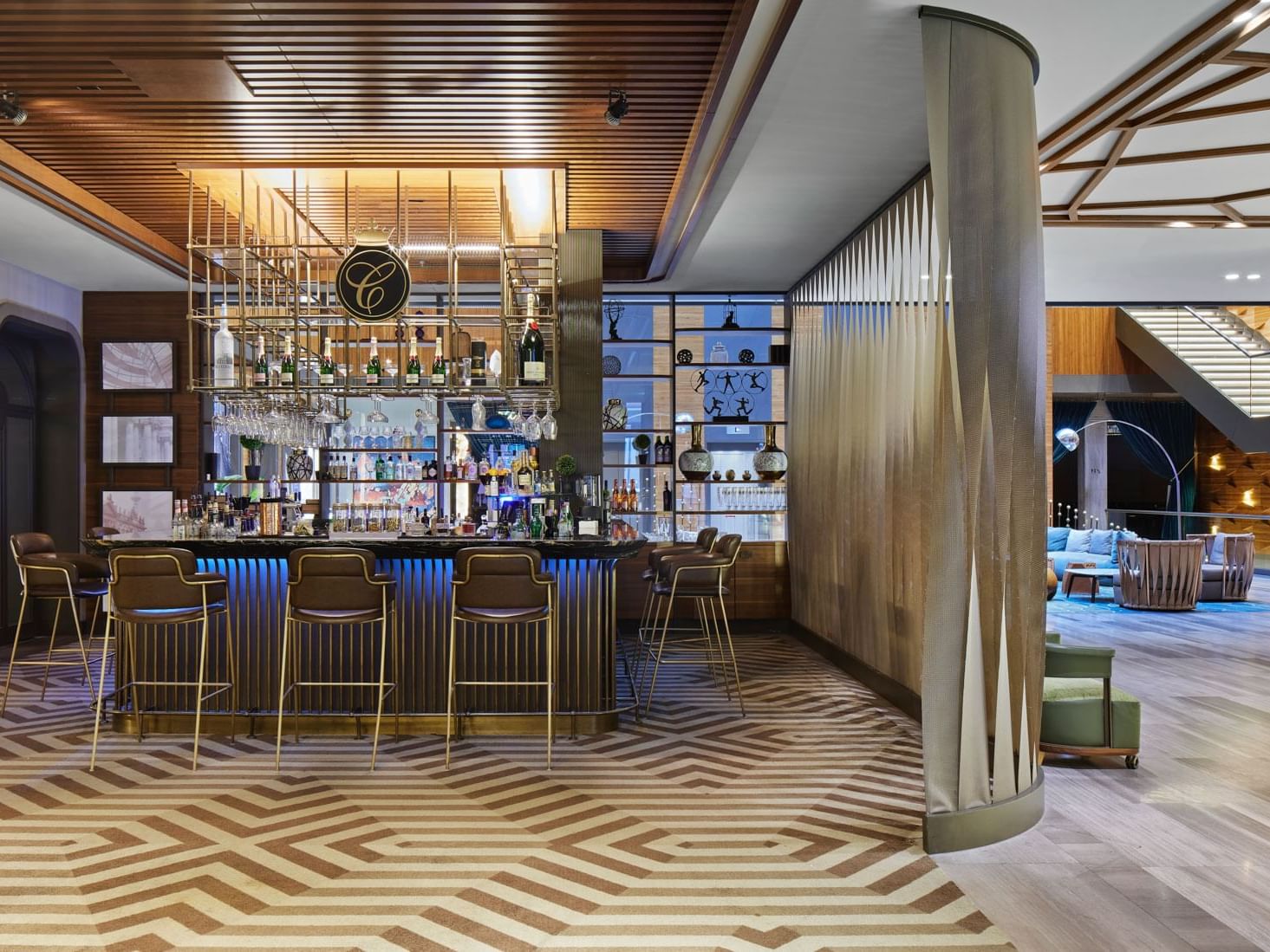 Elegante Bar mit geometrischem Boden, stilvollen Stühlen und gut bestückter Theke – Titanic Chaussee Berlin.