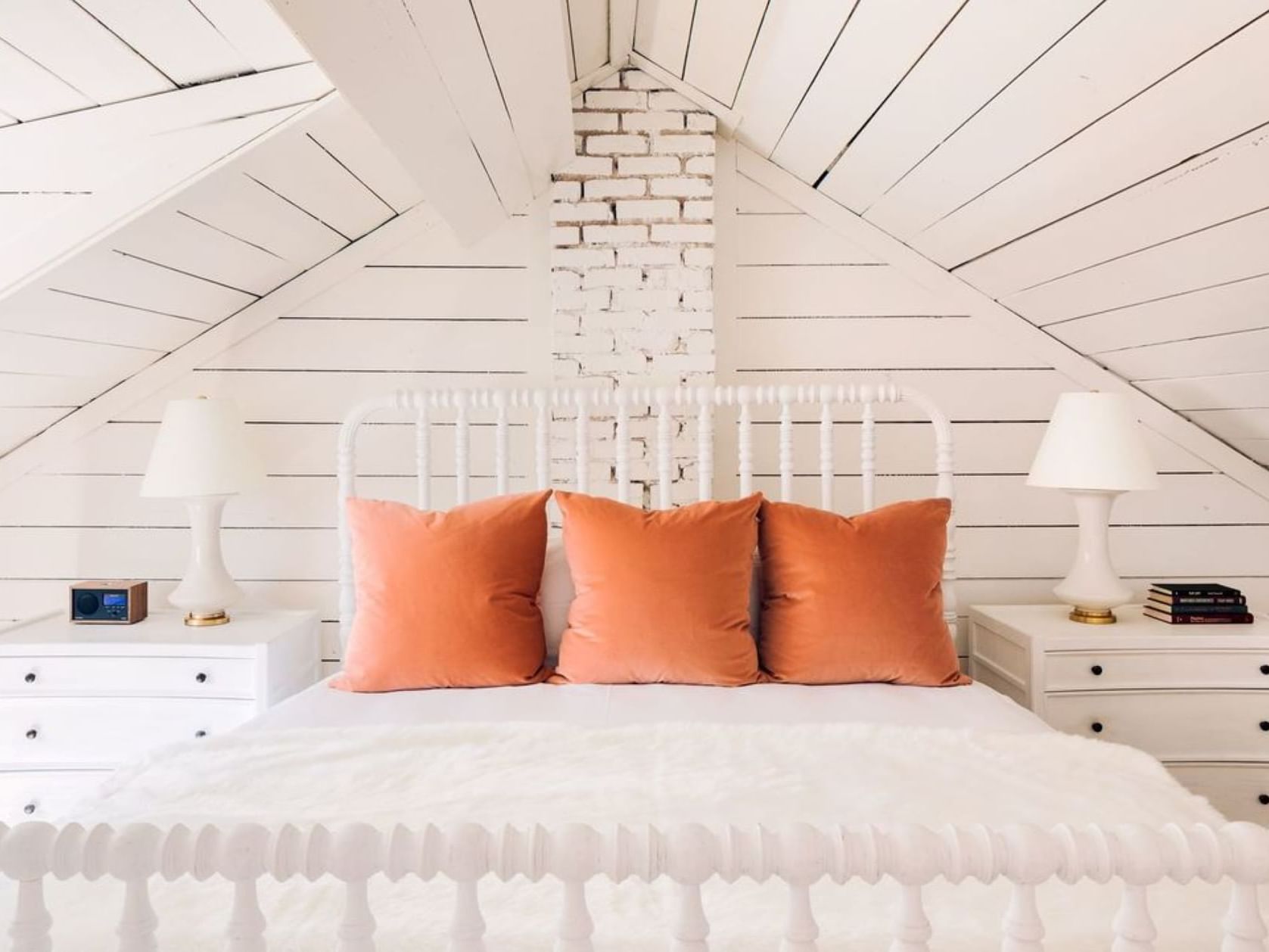 Cozy bed with orange pillows & nightstands in Carriage House at The Clifton