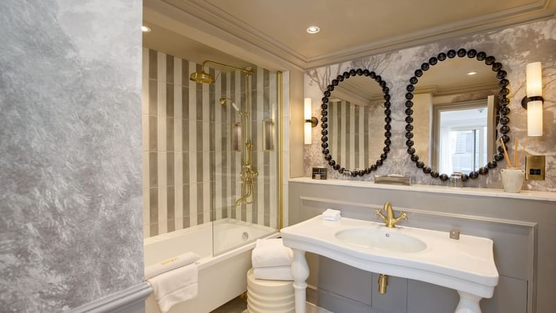 Elegant bathroom with bathtub, double sink vanity, and decorative mirrors at The Capital Hotel, Apartments & Townhouse - London.