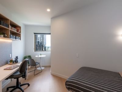A cozy bedroom with desk, chair, and bed at UniLodge Brisbane City.