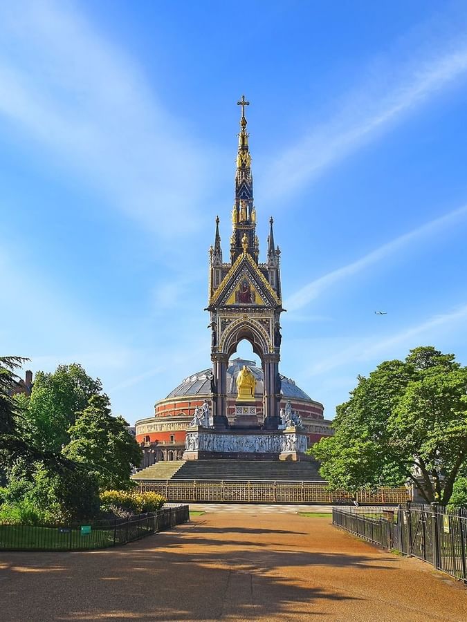Albert Memorial with a gold spire by trees under a blue sky near Warwick Hotels & Resorts