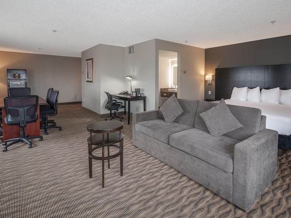 Hotel suite with sofa, desk, and king-sized bed.