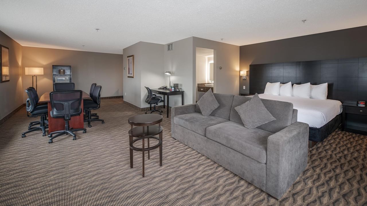 Hotel suite with sofa, desk, and king-sized bed.