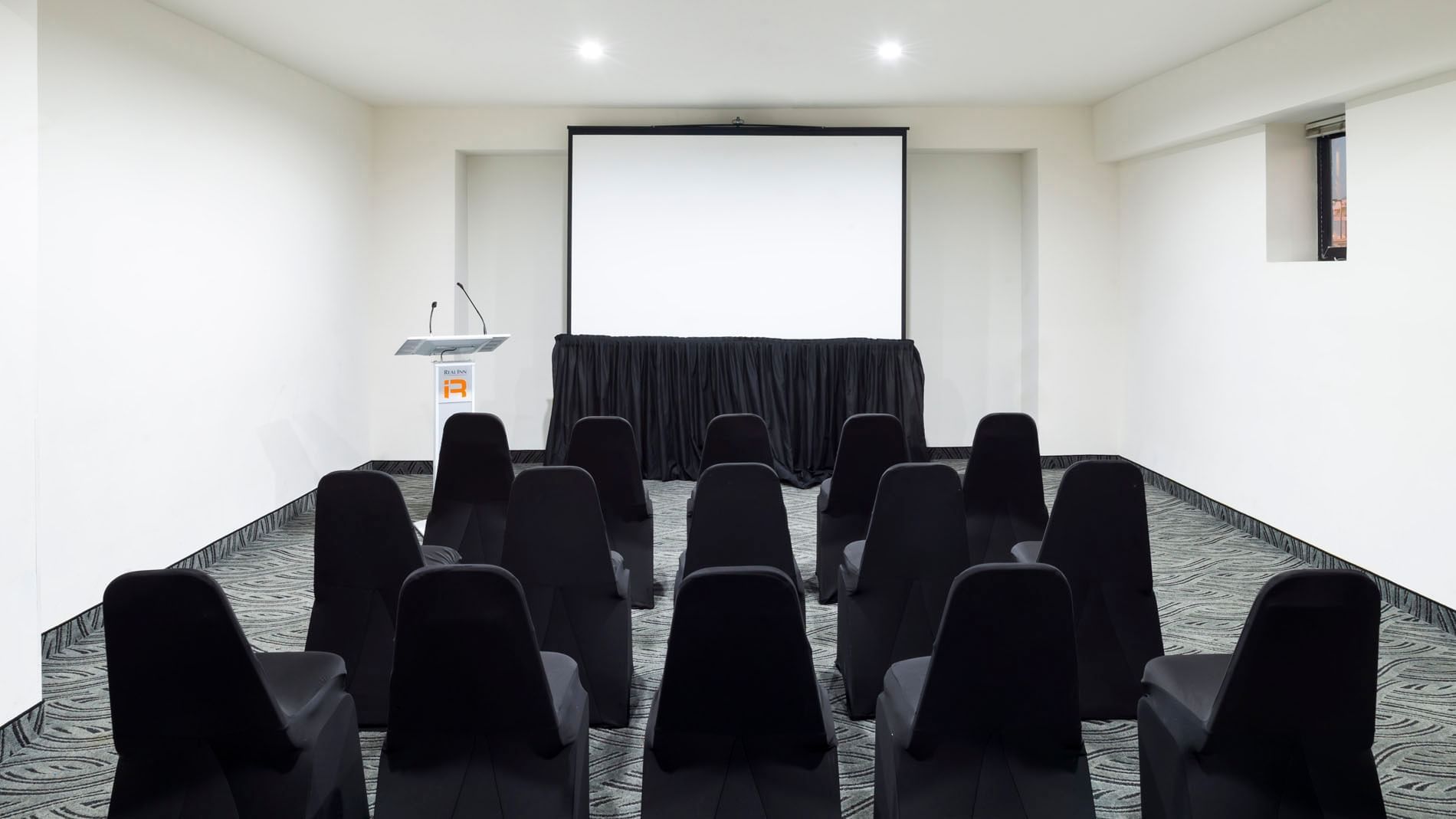 Sala de reuniones Atlanta en el Real Inn Mexicali con sillas y proyector.