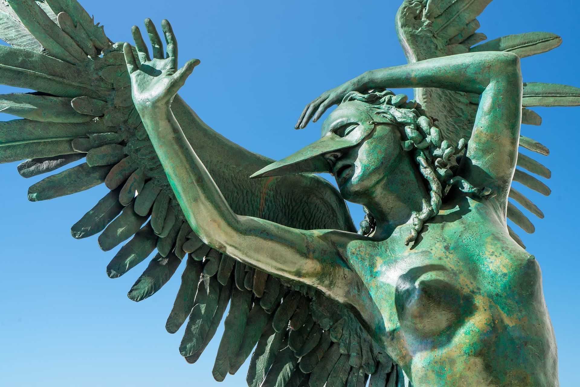 vClose-up of the elegant bronze Harpy sculpture gleaming under a blue sky at Marquis Los Cabos Resort