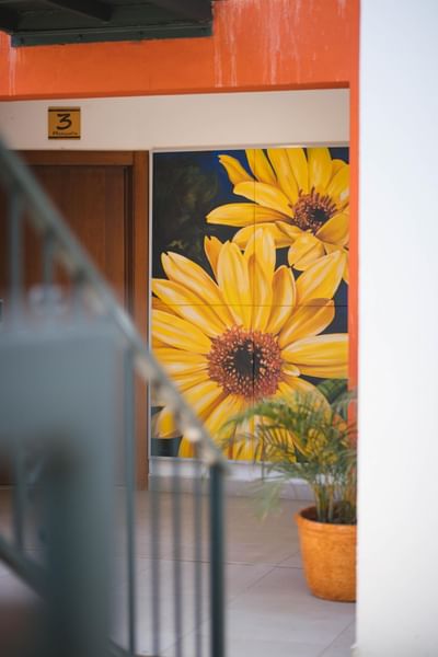 A sunflower painting hanging on a wall in the corridor at Cha Cha Hotel