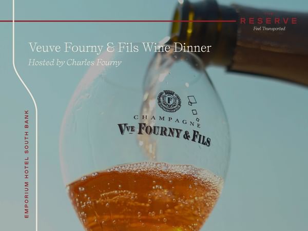Champagne glass with Veuve being poured into it in front of blue sky background