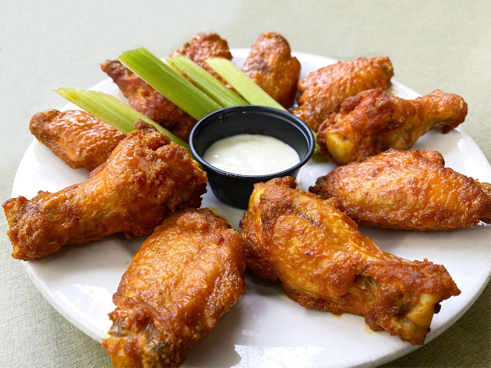 A plate of fried chicken wings with celery sticks and blue cheese dressing