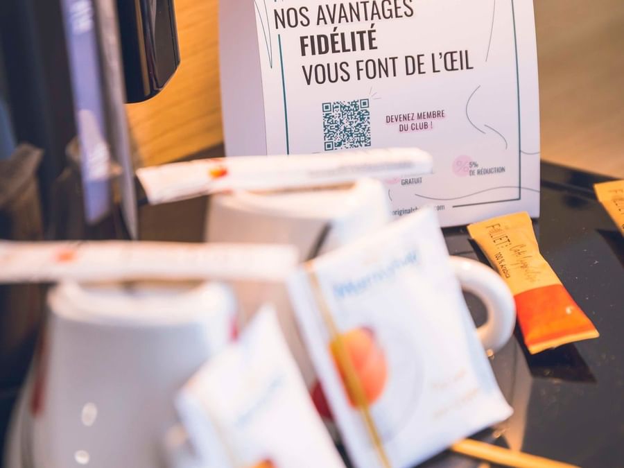 Coffee station with mugs and a flyer from The Originals Club on a tray.