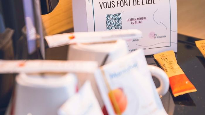 Coffee station with mugs and a flyer from The Originals Club on a tray.
