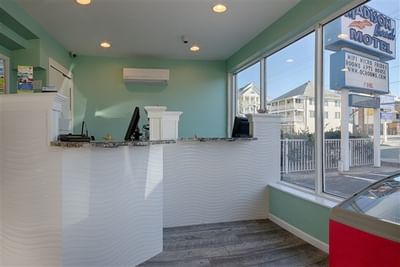 Madison Beach Motel reception area featuring a curved desk, modern decor, and large windows showcasing the outside view