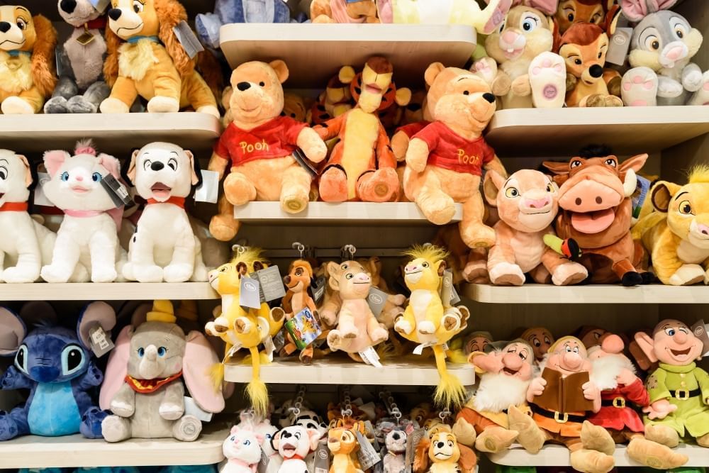 Shelves of assorted Disney stuffed animals including Winnie the Pooh, Dumbo, the 7 Dwarves, Lady and the Tramp, and more.