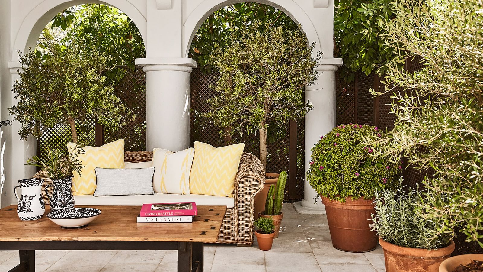 Maria Luisa terrace with wicker seating, cushions, and white arches surrounded by green foliage at Marbella Club
