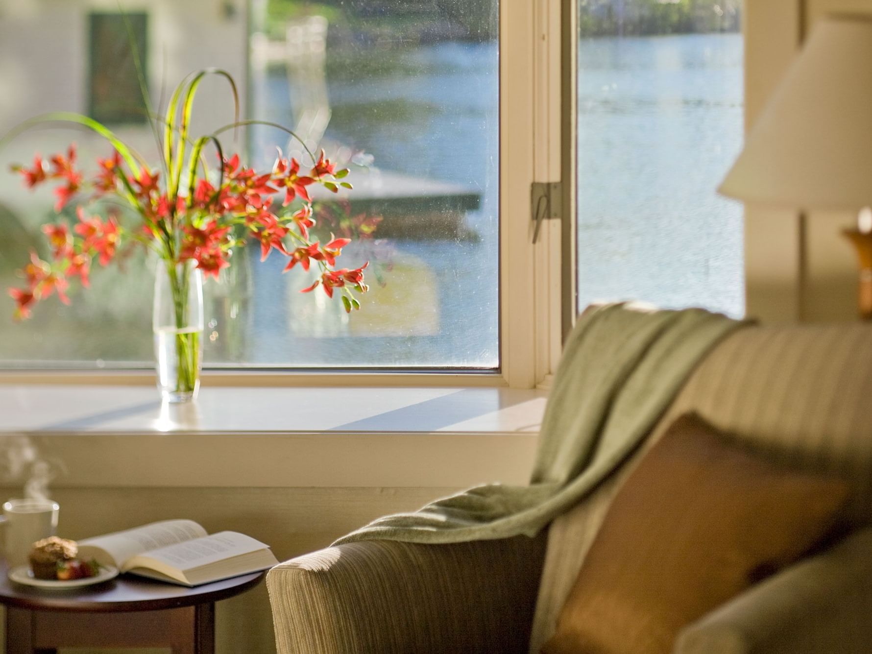 Bay window in Junior Suite with a cozy armchair, a book, and a vase of flowers at High Peaks Resort