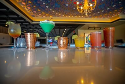 a row of mixed drinks at a bar