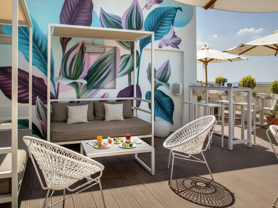Breakfast with a View of Rome
outdoor seating with leaf mural, sofa, chairs, and table with snacks at The Independent