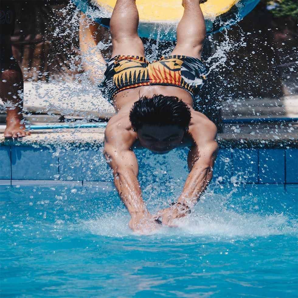 A man jumping into a pool at Falkensteiner Hotels