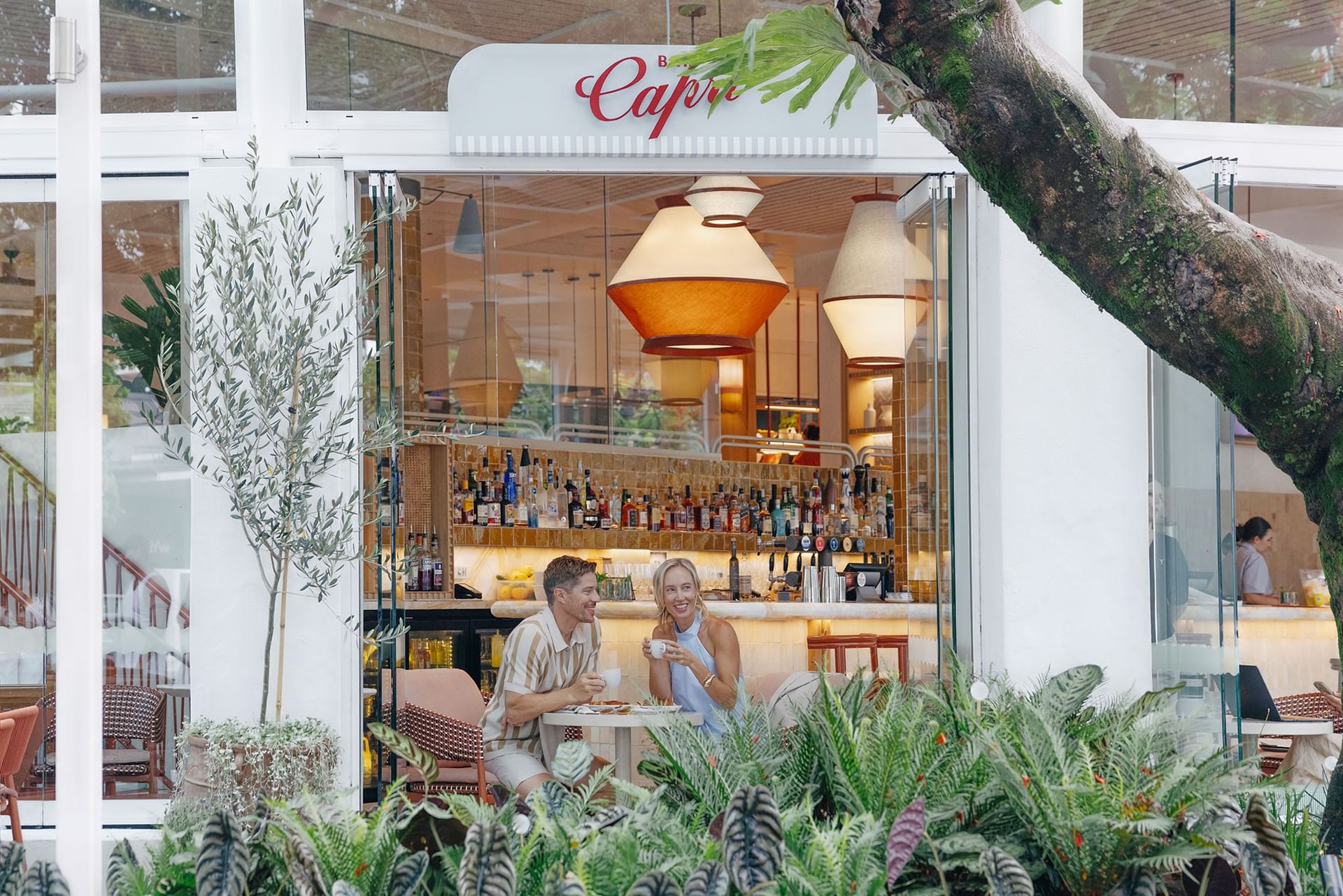 Bar Capri at Elysium Hotels showing a smiling couple enjoying coffee and drinks together at modern bistro table