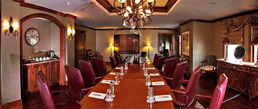 The Boardroom with a long wooden table, leather chairs, and a chandelier, set for a meeting at The Rose Hotel