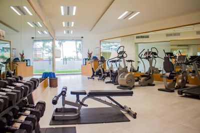 Foto del gimnasio del hotel con diversas máquinas de ejercicio y pesas en el Sunset Plaza Beach Resort