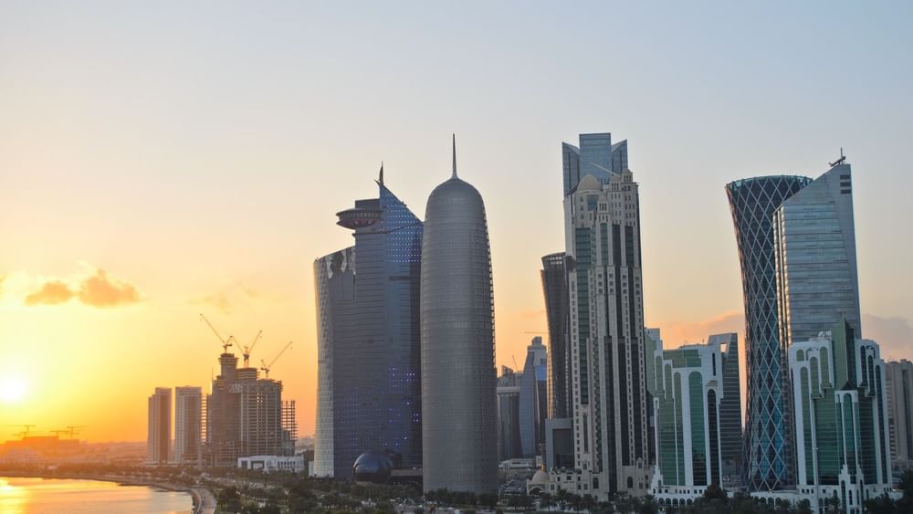 Modern skyline and waterfront at sunset showcasing Doha's urban landscape.