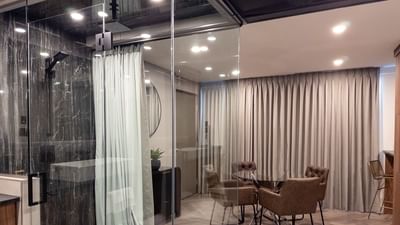 Glass-enclosed shower with modern design, adjacent to a dining area with curtains at Carriage House Hotel Conference Centre