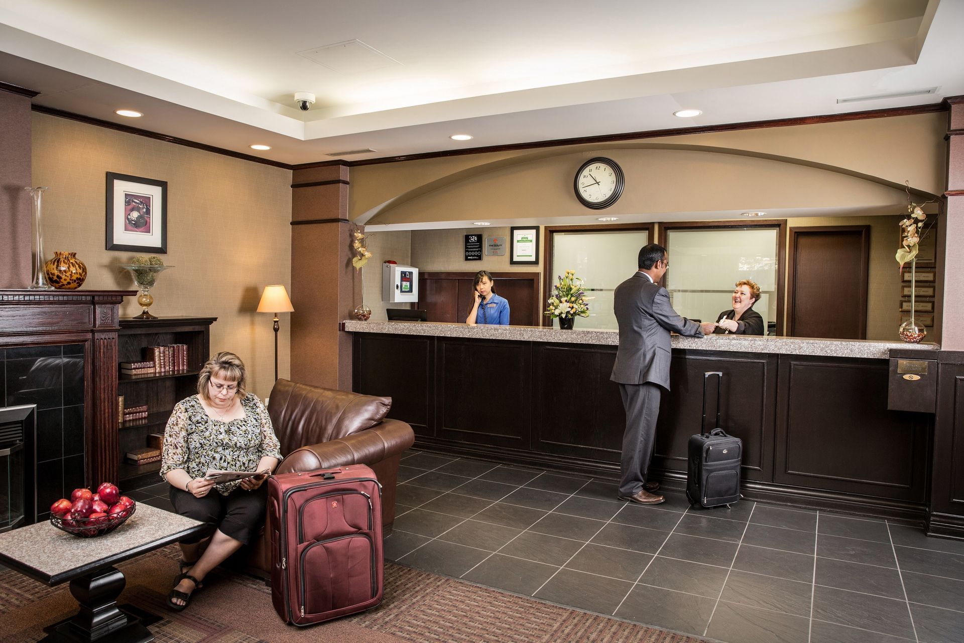 Woman sitting on leather couch and man checking in to hotel